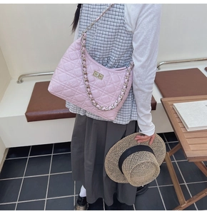Detailed view of pink quilted shoulder bag with gold chain strap on a model