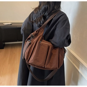Large dark brown nylon tote bag with multi-pocket utility design on model back