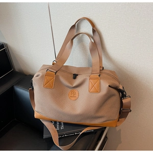 Detail of travel duffel bag showing brown canvas texture and leather handle reinforcements