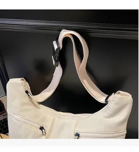 Close-up of white crossbody bag with multi-zipper pockets and adjustable nylon strap