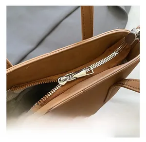 Détail du zip en métal argenté sur sac en cuir mat marron avec doublure à chevrons