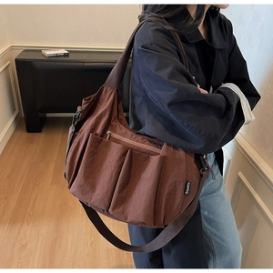Detail of coffee brown large capacity crossbody bag with multiple utility pockets
