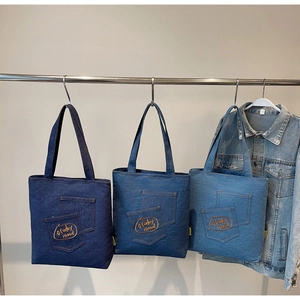 Detailed view of denim tote bags with three blue tones and unique layered pockets design