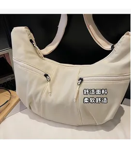 Detail view of cream crescent crossbody bag showing multi-zipper pockets and nylon fabric