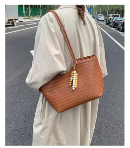 Détail d'un sac cabas tressé marron avec un pendentif à perles colorées élégant