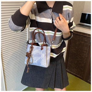 Detail view of light blue marble textured bucket bag with brown handles and scarf decor
