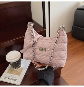Detailed view of pink quilted bucket bag with silver chain strap on a wooden staircase