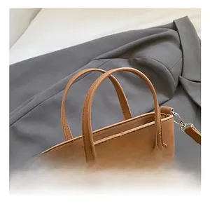 Détail d'un sac à main en daim marron avec poignées et ornement en anneau métal