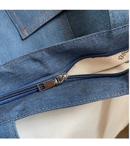Close-up of durable metal zipper and beige herringbone lining on blue denim tote bag