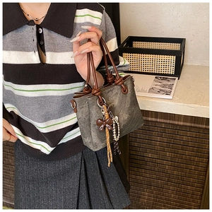 Close-up of vintage bucket bag featuring brown bow tie handle and heart pendant detail