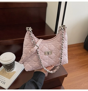 Close-up of pink quilted bucket bag with silver chain strap and metal lock on wooden stairs