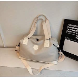 Detail of light grey travel bag with durable nylon fabric and white leather trim accents