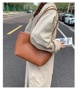 Photo lifestyle d'un grand sac cabas tressé marron porté à l'épaule en extérieur