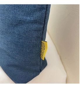 Detailed macro view of denim fabric stitching and yellow brand label on canvas tote bag