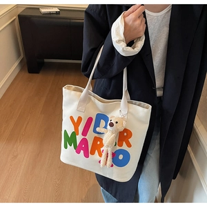 White canvas tote bag with colorful YIDMAR text and cute plush bear keychain detail