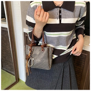 Detailed view of retro brown bucket bag with knotted handles and metallic butterfly charms