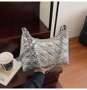 Macro view of silver quilted shoulder bag with metallic finish and chain strap details