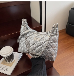 Detail of silver quilted chain bag with turn-lock clasp and metallic crescent shape
