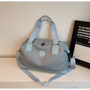Close-up of light blue travel bag texture with round logo and reinforced strap