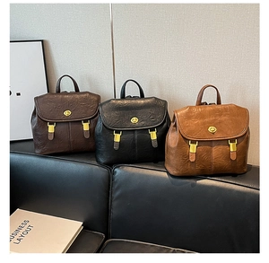 Detailed view of vintage leather backpacks in brown and black with gold twist locks