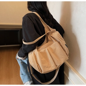 Detailed view of beige nylon crossbody bag featuring large functional utility pockets