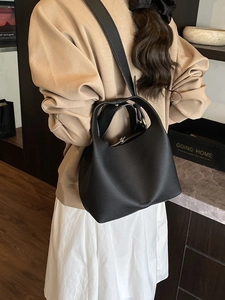 Classic black litchi pattern leather bucket bag shown as a crossbody on a female model