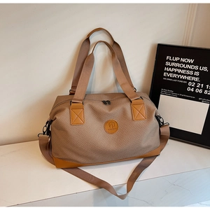 Detail of khaki checkered travel bag with reinforced leather handles and shoulder strap