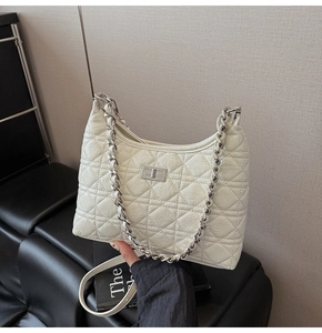 Detail of white quilted handbag showing silver chain strap and metal turn-lock closure