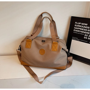 Travel duffel bag featuring earth-tone woven fabric with reinforced brown leather corners