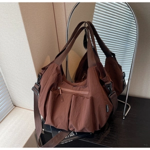 Detail view of brown nylon tote bag with multi-pocket design and pleated texture