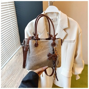 Close-up of retro bucket bag with knotted leather handle and decorative bow charm