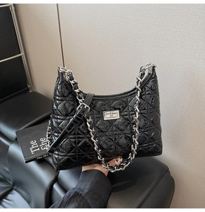 Detail of black quilted leather shoulder bag with silver turn-lock and chain strap