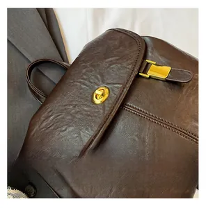 Detail of dark brown leather backpack with vintage texture and gold twist-lock closure