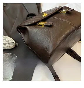 Close-up of brown leather backpack with lychee texture and three gold metal buckles
