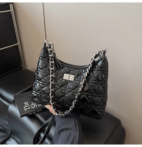 Close-up of black quilted leather bucket bag with silver chain and metallic turn-lock
