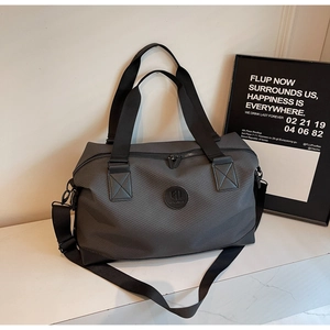 Detail of dark grey travel bag showing carbon fiber texture and nylon handles