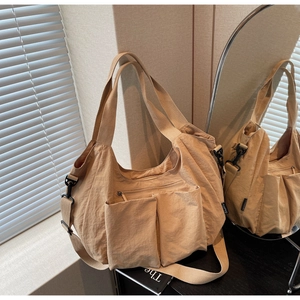 Detail of light brown large tote bag showing outer pockets and nylon fabric texture