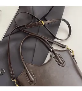 Detail of dark brown leather bucket bag showing golden hardware and adjustable strap
