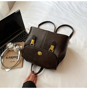 Detail of vintage brown leather backpack with gold buckles on white bedding