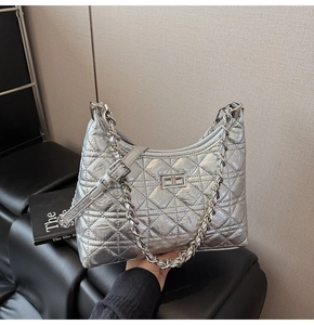 Detail view of silver quilted moon bag with metallic chain and stylish twist lock closure