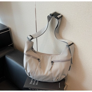 Détail macro d'un sac demi-lune en nylon gris clair avec poches zippées et bandoulière large