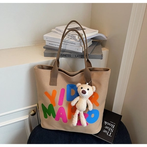 Detail of canvas tote bag with large colorful letters and cute white plush bear charm