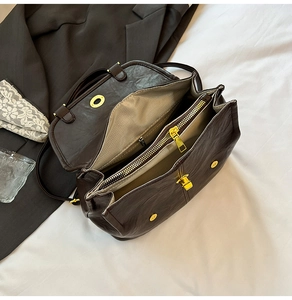 Top view of open dark brown backpack showing three compartments and gold zipper detail