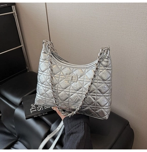Detailed view of silver quilted chain bag with metallic finish and metal turn-lock closure