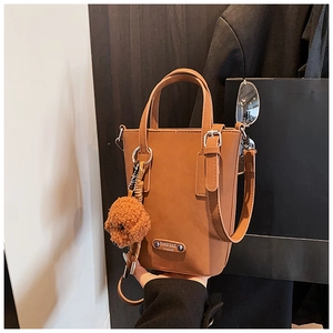 Detail of a brown leather crossbody phone bag with cute dog charm and silver logo plaque