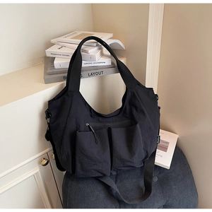 Close-up of black nylon tote bag with multi-pocket design and wide shoulder strap