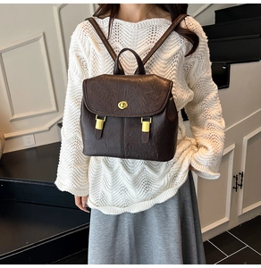 Detail of dark brown retro leather backpack featuring golden twist lock and textured finish