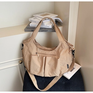 Detail of khaki nylon tote bag with multiple front pockets and smooth zipper closure