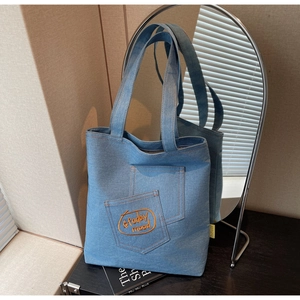Close-up of denim tote bag with layered pockets and orange today mood embroidery