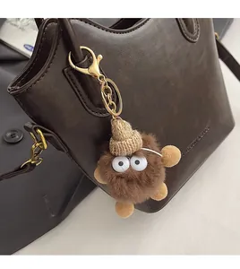 Brown plush charm with knit hat and large eyes attached to a vintage leather handbag